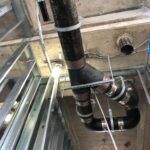 Overhead copper pipe runs installed across a commercial building ceiling