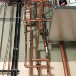 Copper piping network installed along a wall in a commercial mechanical room