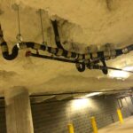 Black supply pipe routed through spray-foam insulated ceiling in a commercial space